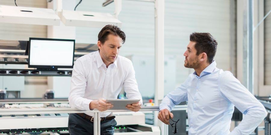 two businessmen with tablet talking in modern fact