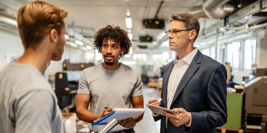 mid-adult engineer and two metal workers communicating