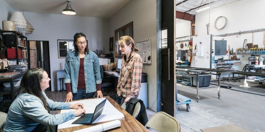 three women gathered around table in office area